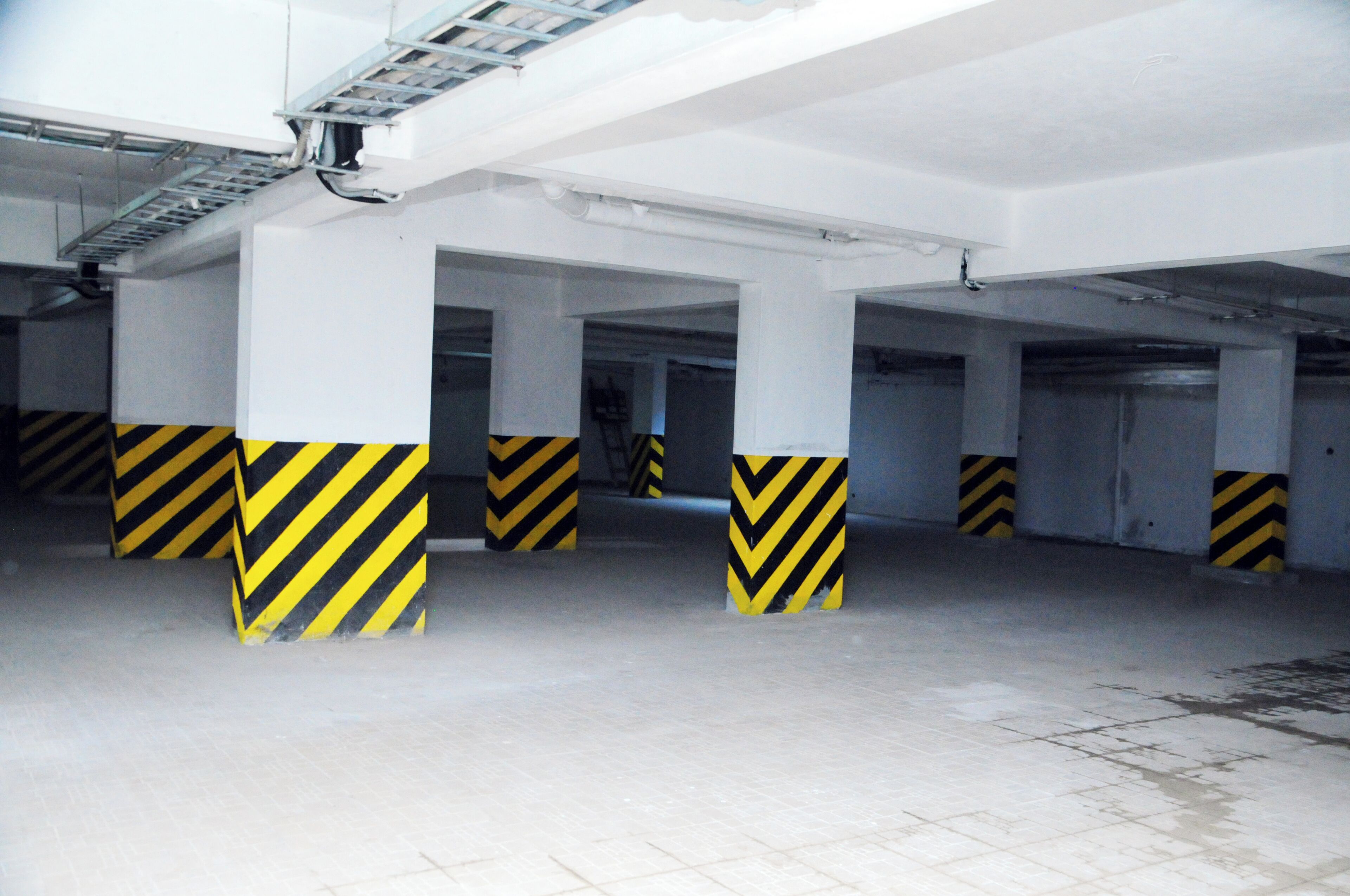 A multi-level parking garage with white pillars and yellow and black striped bases.
