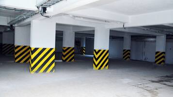 A multi-level parking garage with white pillars and yellow and black striped bases.