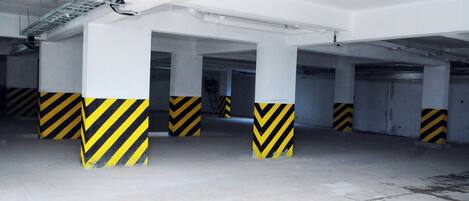 A multi-level parking garage with white pillars and yellow and black striped bases.