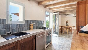 Eine moderne Küche mit Backofen, Spüle und Essbereich mit Holztisch und Stühlen.