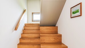 Una escalera de madera con un pequeño ventanal en la parte superior.