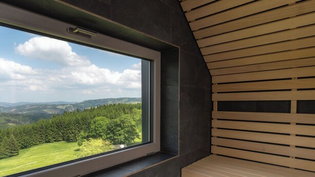 Un interior moderno con un ventanal amplio que ofrece vistas a un paisaje verde y colinas.