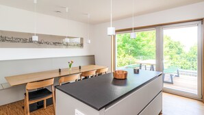 Una cocina moderna con una isla central, sillas de madera y luces colgantes.
