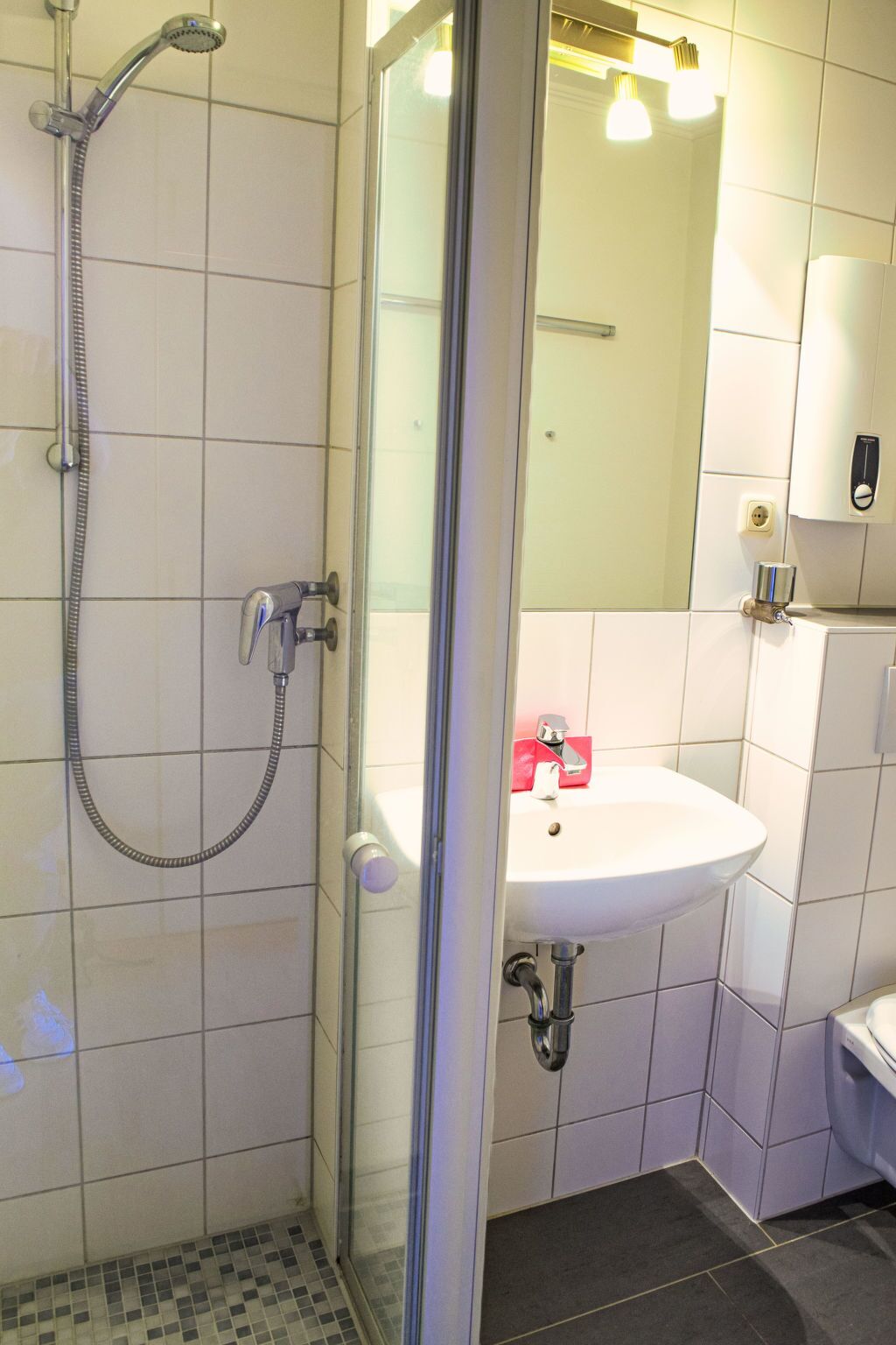 Une salle de bain moderne avec une douche à parois de verre, un lavabo blanc et un miroir au-dessus.