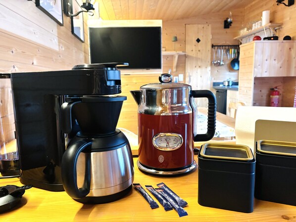 A kitchen with a coffee maker, a kettle, and a thermos on a wooden table. - Chalet 'Josef' with Private Terrace, Private Garden and Wi-Fi (Braunsbedra)