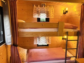 A bunk bed room with wooden walls, a window with curtains, and a small table. - Chalet 'Josef' with Private Terrace, Private Garden and Wi-Fi (Braunsbedra)