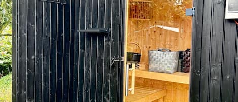 A wooden cabin with a sliding door, a small porch, and a shelf with items.