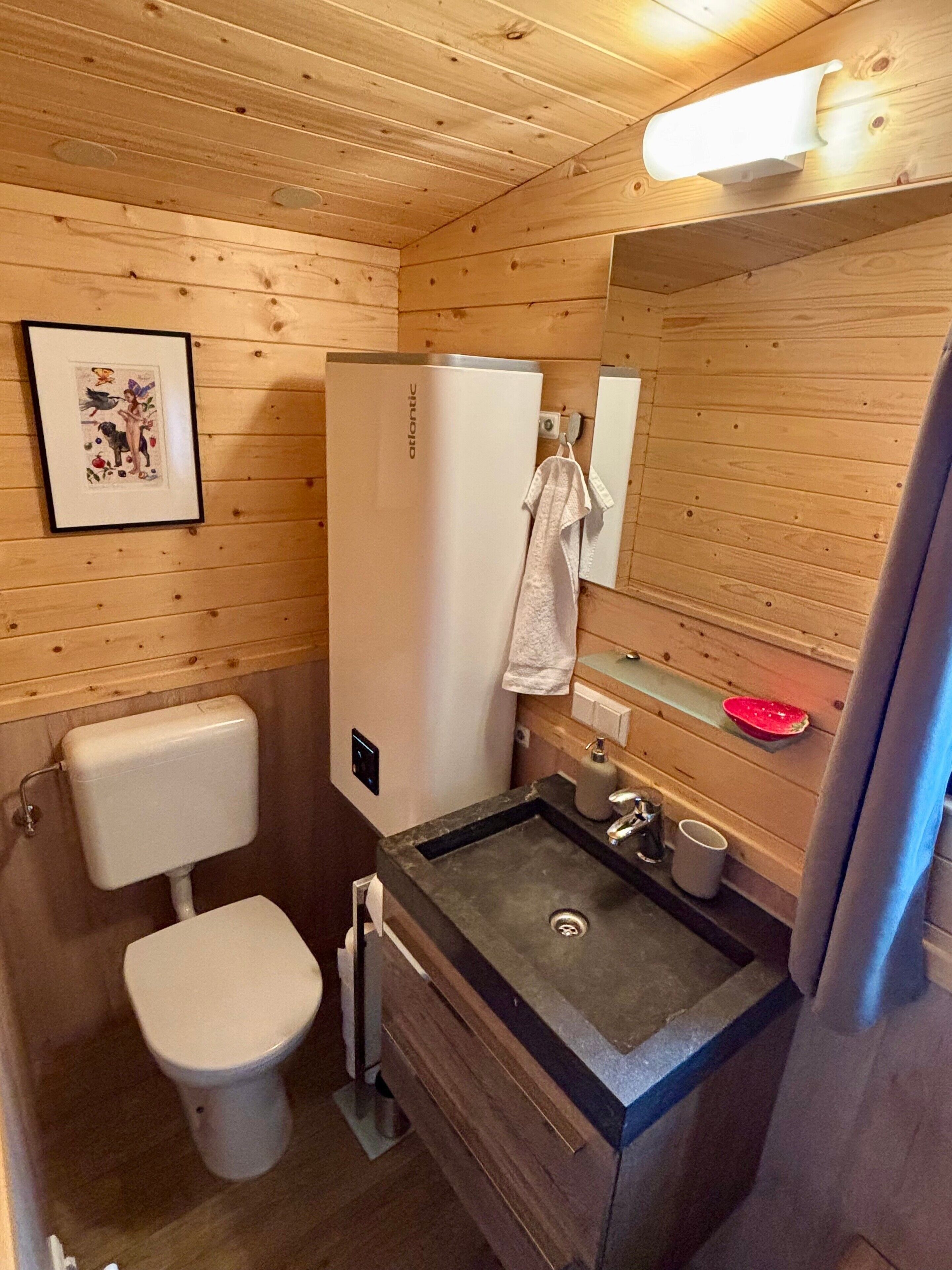 A compact bathroom with a toilet, sink, and a white toilet paper holder.