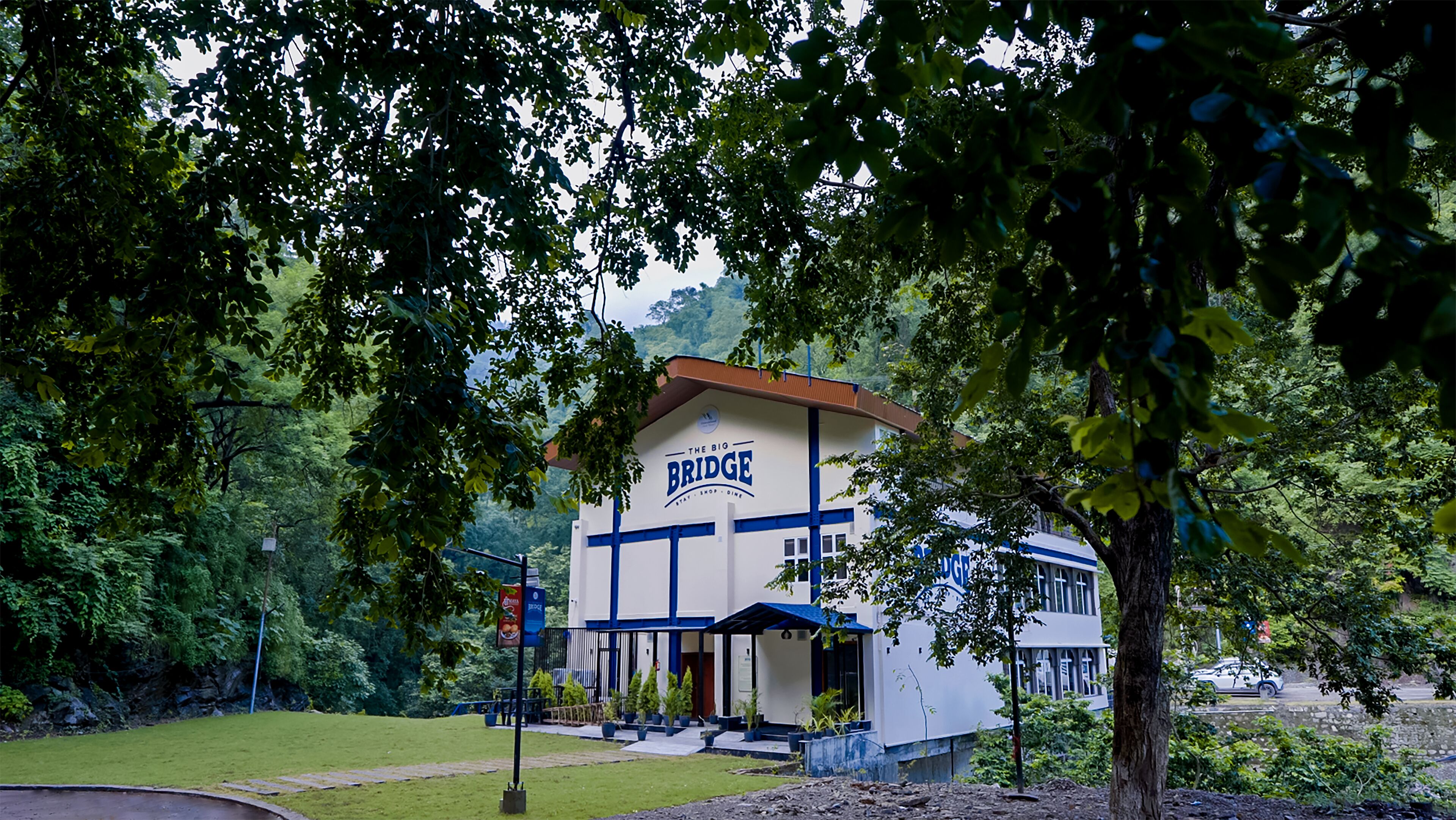 Un edificio con un letrero que dice "The Big Bridge" rodeado de árboles.