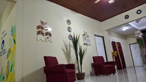 A hotel lobby with red chairs, a potted plant, and decorative wall art. - Hostal Casa Habana  (Managua)