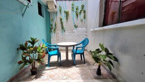 A small patio with a round table and four blue chairs, surrounded by potted plants. - Hostal Casa Habana  (Managua)