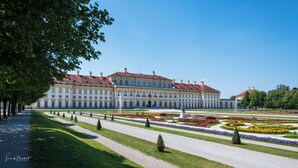 A large, classical building with symmetrical architecture, a formal garden with geometric flower beds, and a clear sky. - Studio 1 - Apartments at the castle (Oberschleißheim)