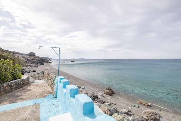 Une promenade en bord de mer avec des escaliers menant à la plage, une vue dégagée sur la mer et un terrain rocheux.