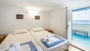 A hotel room with two beds, a bench outside, and a view of the sea. - Description of Villa Sissy (Κεραμε)