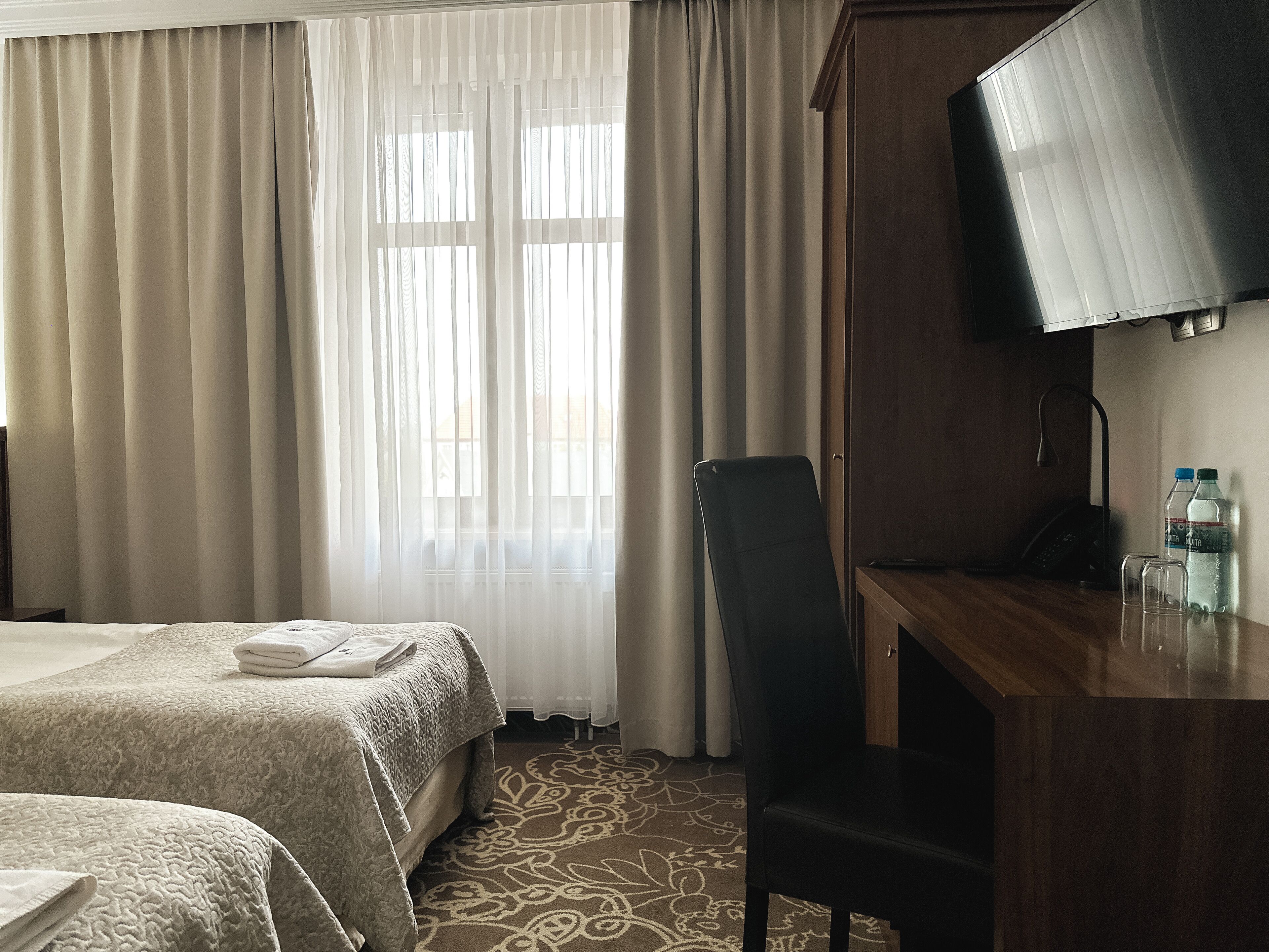 Une chambre d’hôtel avec deux lits, un bureau avec une télévision et une chaise.