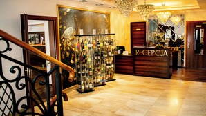 A reception area with a wooden reception desk, a chandelier, and a wall with a large abstract painting.
