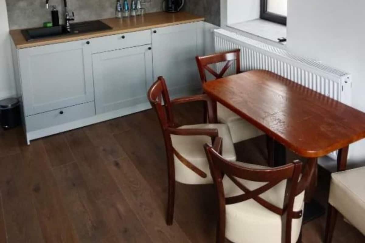 A modern kitchen with white cabinets, a wooden countertop, and a dining table with chairs.