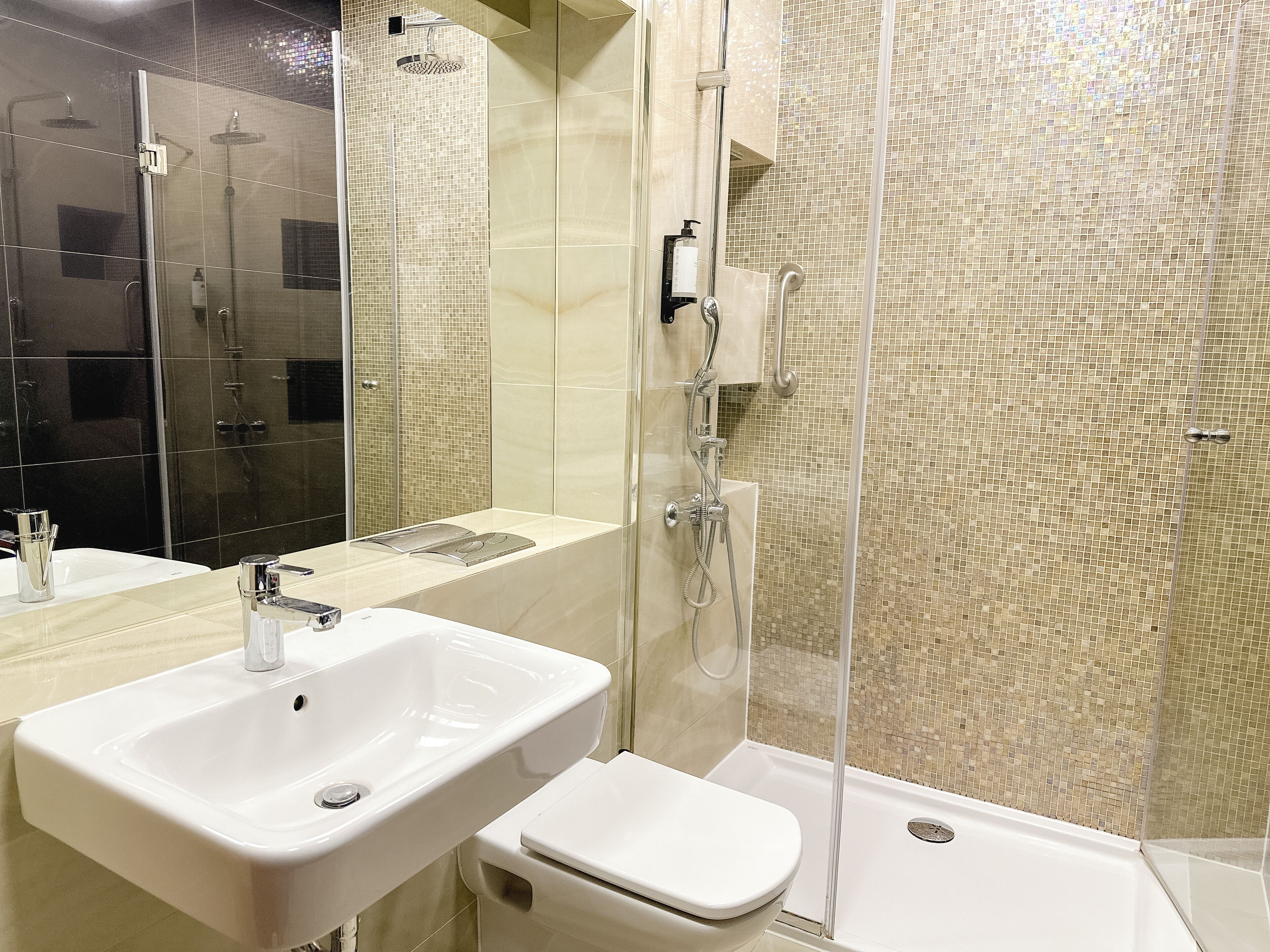 A modern bathroom with a white sink, toilet, and shower area.