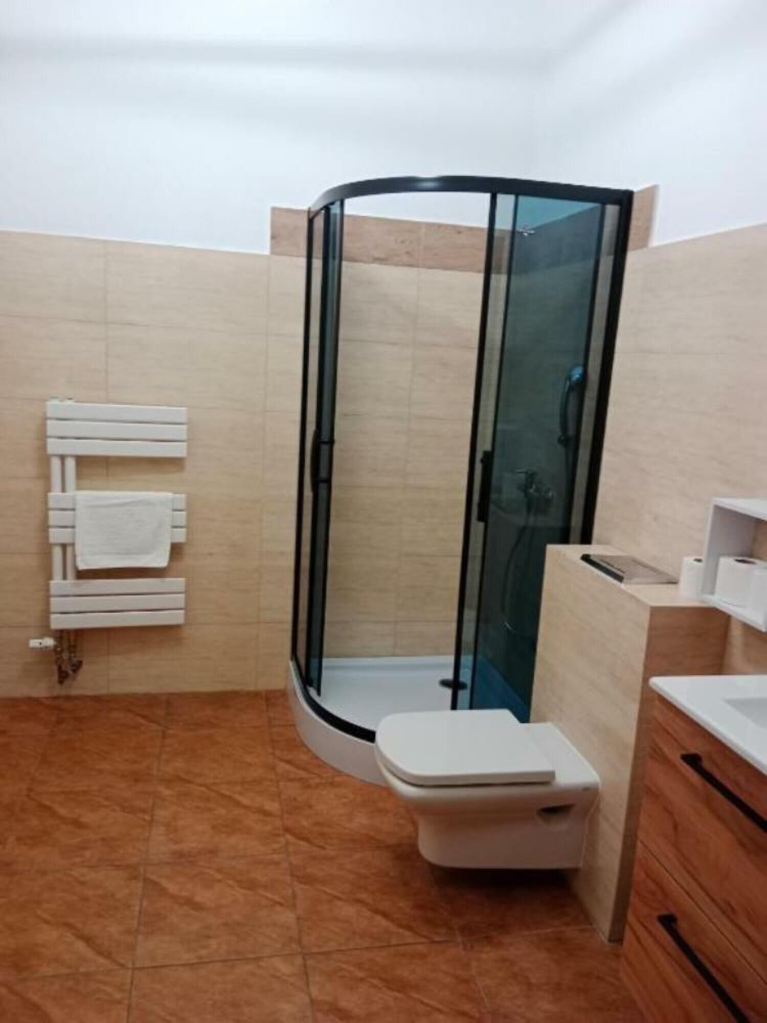 Une salle de bain moderne avec une douche à parois de verre, des toilettes blanches et un meuble-lavabo en bois.