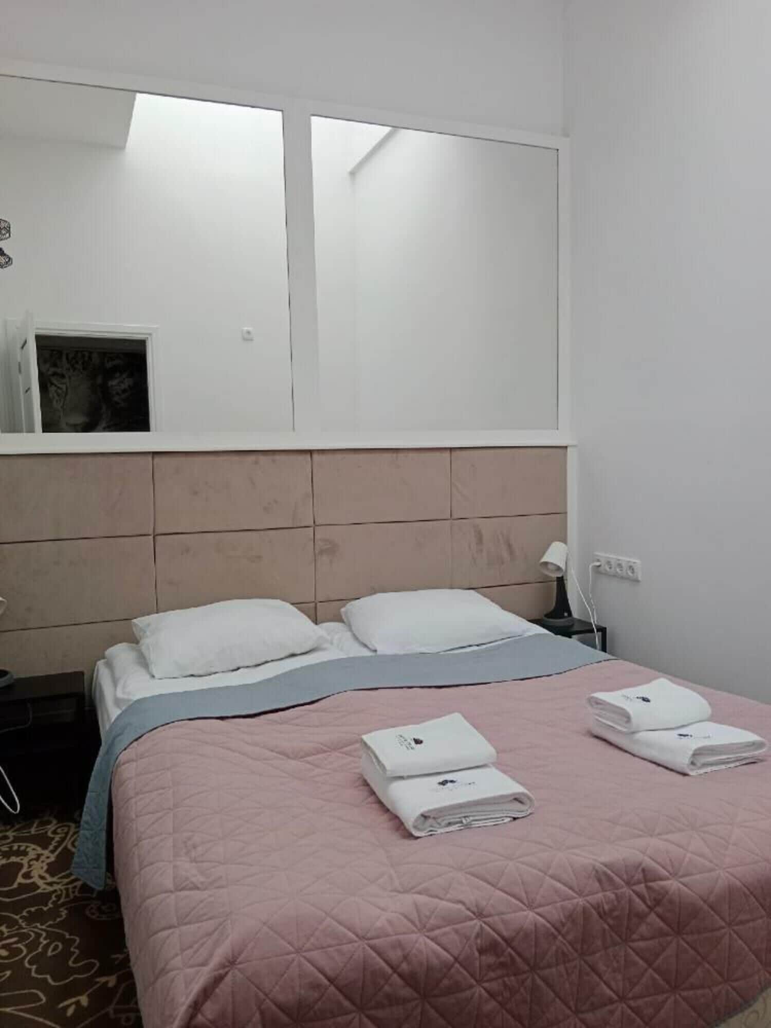 A hotel room with a bed, a nightstand, a lamp, and a window with a view.