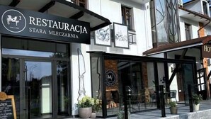 A restaurant and hotel with glass fronts, outdoor seating, and a sign for 'Hotel Pruski'.