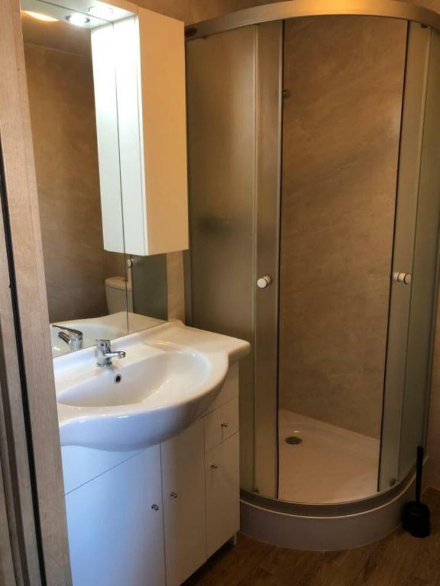 A bathroom with a white sink, a mirror, and a glass-enclosed shower.