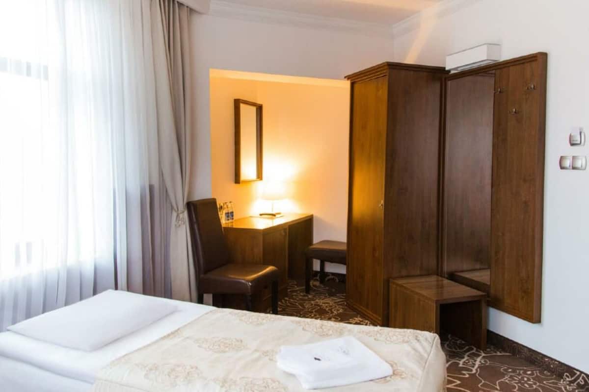 A hotel room with a bed, a desk, a chair, and a wardrobe.