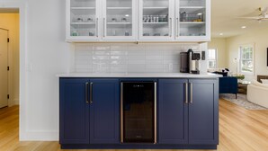 A modern kitchen with dark blue cabinets, white upper cabinets, and a built-in dishwasher.
