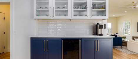 A modern kitchen with dark blue cabinets, white upper cabinets, and a built-in dishwasher.