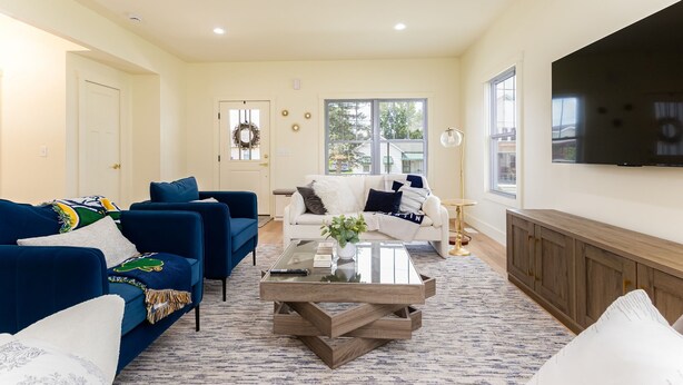 A living room with a blue sofa, white sofa, and a coffee table with a plant.