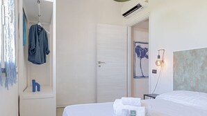 Une chambre d’hôtel avec un lit, un porte-peignoir suspendu, une petite table avec une lampe et un tableau au mur.