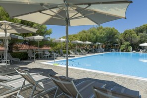 A poolside area with lounge chairs and umbrellas, surrounded by trees and a tiled roof. - Discover the joy of a holiday in Castiglioncello, surrounded by nature and overlooking the stunning Etruscan Coast.Our apartment is located in a seaside residence with direct access to a private beach and a pool, perfect for relaxing between dips. Scenic (Rosignano Marittimo)