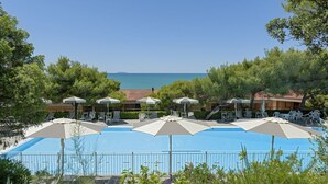 Une piscine dotée de parasols, de chaises longues et offrant une vue sur la mer.