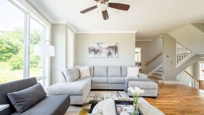 A spacious living room with a grey sectional sofa, a marble coffee table, and a ceiling fan.