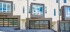 Un edificio residencial de varios pisos con diseño moderno, con ventanas amplias y puertas de garaje.
