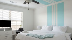 Un dormitorio con cama, escritorio, televisor y ventilador de techo.