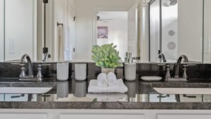 Un baño moderno con dos lavamanos, un espejo grande y una planta en maceta.