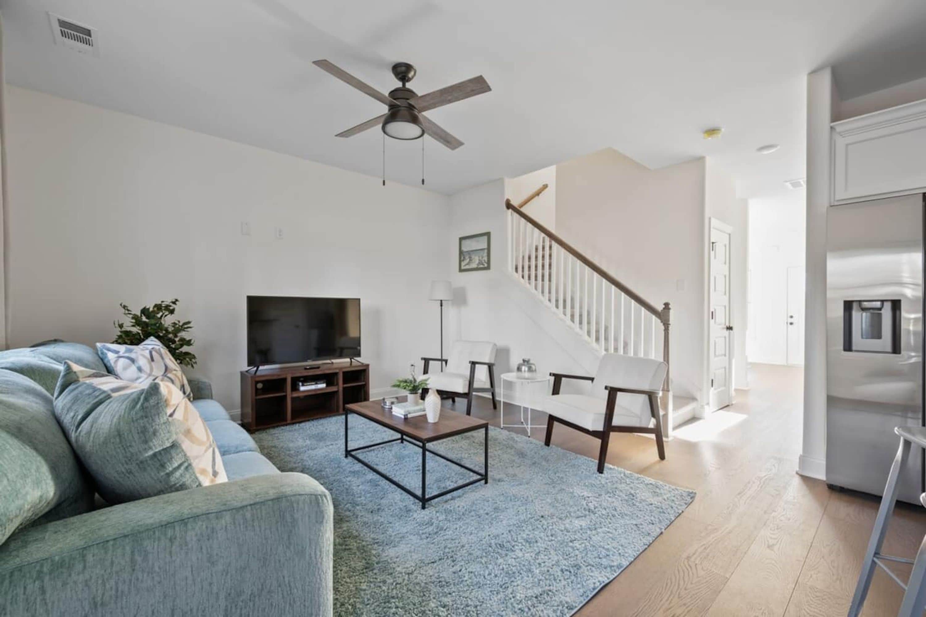 Una sala de estar moderna con sofá, mesa de centro, televisor y una escalera que lleva a otra habitaci ón.