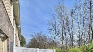 Una propiedad residencial con un camino de hormigón que lleva a una cerca blanca.