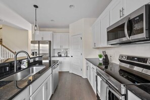 A modern kitchen with stainless steel appliances, white cabinetry, and a black countertop. - 1 King 2 Queens Garage Yard Washer Dryer (Old Hickory)