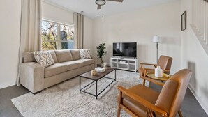 Een woonkamer met een bank, salontafel, televisie en een plafondventilator.