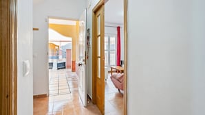 Un pasillo con piso de baldosas que conduce a una habitación con cama y cortina roja.