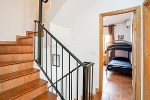 A staircase with brown tiles and black railings leading to a room with a bunk bed. - Apartment in Lepe with Pool and Garden (Lepe)