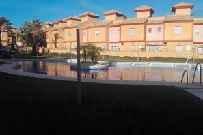 A hotel with a swimming pool, palm trees, and a clear blue sky. - Apartment in Lepe with Pool and Garden (Lepe)