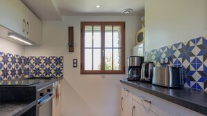 A modern kitchen with a black countertop, stainless steel appliances, and patterned tile backsplash.