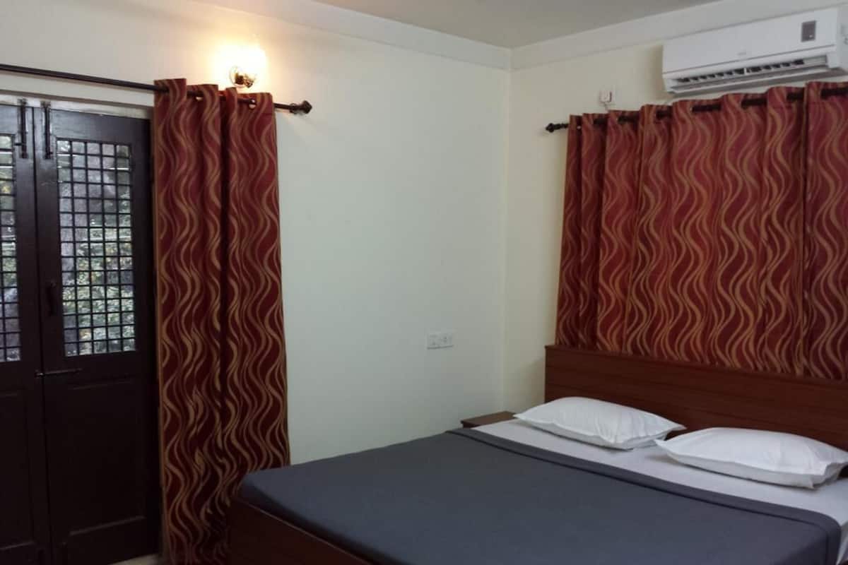 A bedroom with a bed, curtains, and an air conditioning unit.
