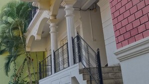 A multi-story building with balconies, a staircase, and a brick section. - VARSHA ENCLAVE WHITE HOUSE (Mysore)