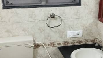 A bathroom with a toilet, sink, and window with blinds.