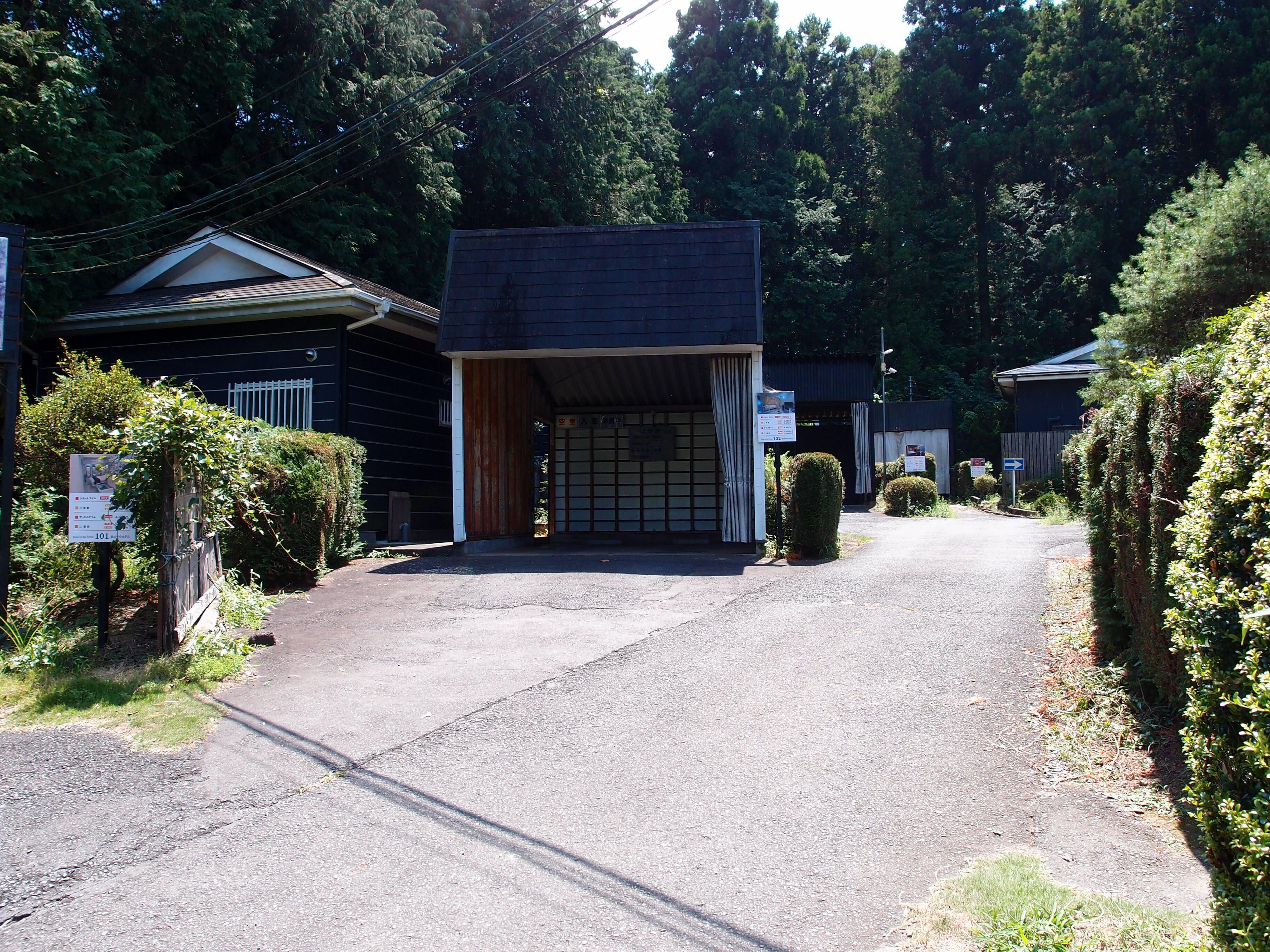 A building with a covered entrance, a gravel driveway, and a signboard.