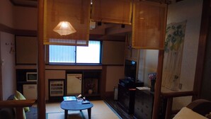 Una habitación japonesa tradicional con suelo de tatami, una mesita baja, un televisor y un futón.